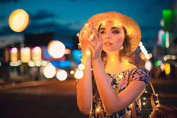 Image showing Beautiful young woman smiling and talking garlands of lights at city