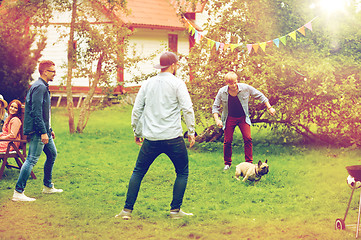 Image showing happy friends playing with dog at summer garden