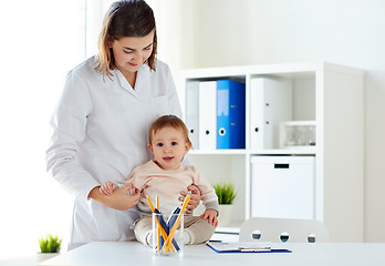 Image showing happy doctor or pediatrician with baby at clinic