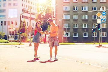 Image showing teenage couple riding skateboards on city street