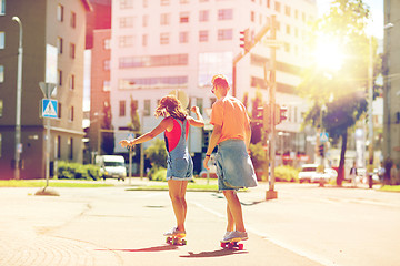 Image showing teenage couple riding skateboards on city street