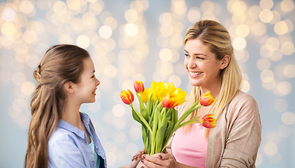 Image showing happy girl giving flowers to mother over lights