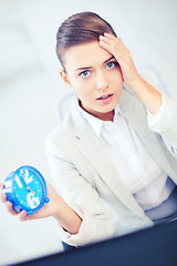 Image showing stressed businesswoman holding clock