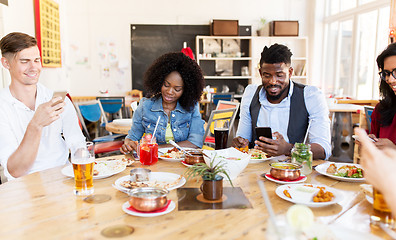 Image showing happy friends with smartphones at restaurant