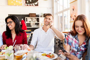 Image showing happy friends with smartphones at restaurant