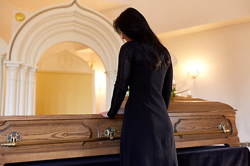 Image showing sad woman with coffin at funeral in church