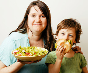 Image showing mature woman holding salad and little cute boy with hamburger te