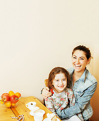 Image showing young mother with daughter on kitchen drinking tea together hugging eating celebration cake on birthday party