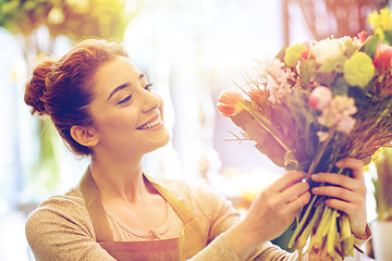 Image showing smiling florist woman making bunch at flower shop