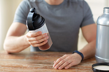 Image showing close up of man with protein shake bottle and jar