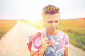 Image showing sad young hippie man walking along country road