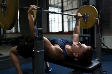 Image showing young man flexing muscles with barbell in gym