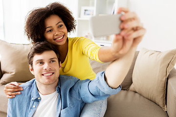 Image showing happy couple with smartphone taking selfie at home