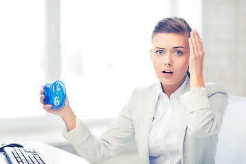 Image showing stressed businesswoman holding clock