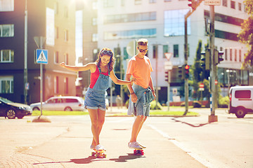 Image showing teenage couple riding skateboards on city street