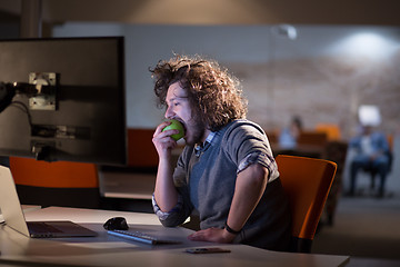 Image showing man eating apple in his office