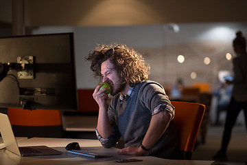 Image showing man eating apple in his office