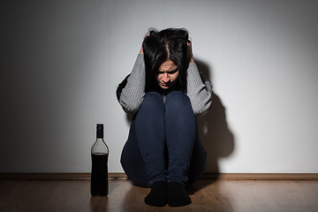 Image showing woman with bottle of alcohol crying at home