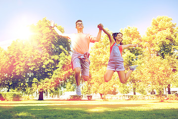 Image showing happy teenage couple jumping at summer park