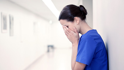 Image showing sad or crying female nurse at hospital corridor