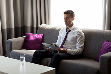 Image showing businessman reading newspaper at hotel room