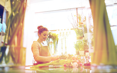 Image showing smiling florist woman making bunch at flower shop