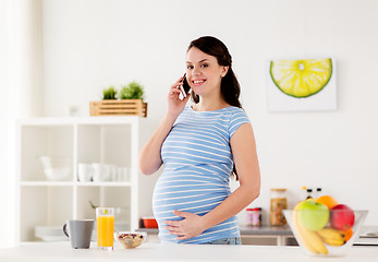 Image showing happy pregnant woman calling on smartphone at home