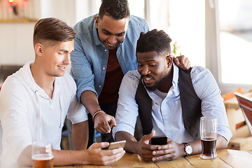 Image showing male friends with smartphone drinking beer at bar