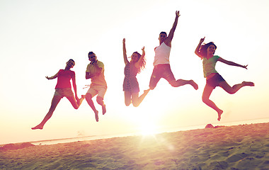 Image showing smiling friends dancing and jumping on beach