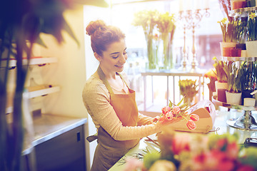 Image showing smiling florist woman making bunch at flower shop