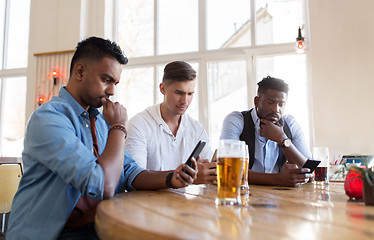 Image showing male friends with smartphone drinking beer at bar