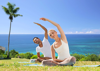 Image showing happy couple making yoga exercises outdoors