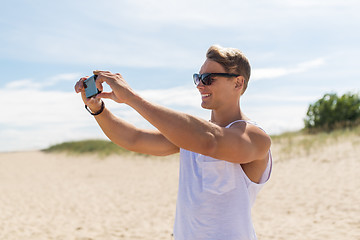 Image showing man with smartphone photographing on summer beach