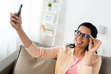 Image showing happy woman taking selfie with smartphone at home