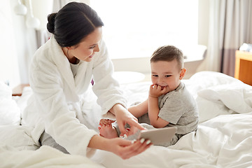 Image showing mother and son with smartphone in bed at hotel