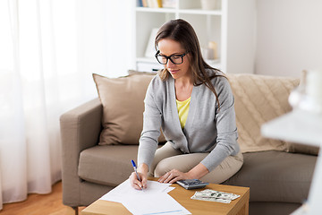 Image showing woman with money, papers and calculator at home