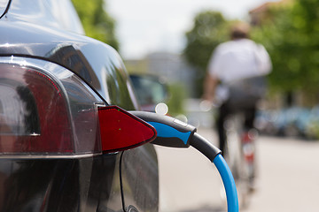 Image showing Power supply plugged into an electric car being charged.