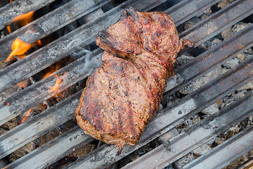 Image showing Beef steaks on grill with flames.