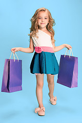 Image showing The cute little caucasian brunette girl in dress holding shopping bags