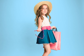 Image showing The cute little caucasian brunette girl in dress holding shopping bags