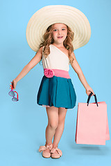 Image showing The cute little caucasian brunette girl in dress holding shopping bags