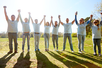 Image showing group of happy volunteers holding hands outdoors