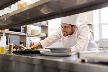 Image showing happy male chef cooking food at restaurant kitchen