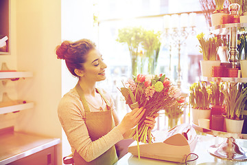 Image showing smiling florist woman making bunch at flower shop