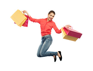 Image showing smiling young woman with shopping bags jumping