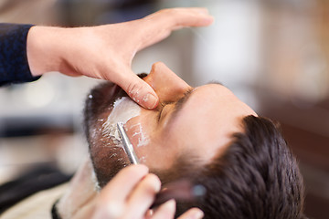 Image showing man and barber with straight razor shaving beard