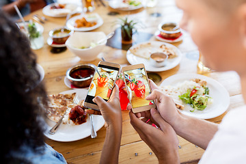 Image showing couple picturing drinks by smartphones at bar