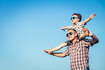 Image showing Dad and son in sunglasses playing in the park at the day time.