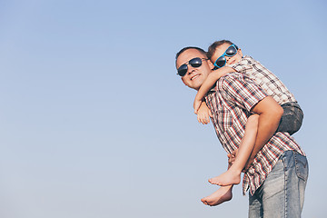 Image showing Dad and son in sunglasses playing in the park at the day time.