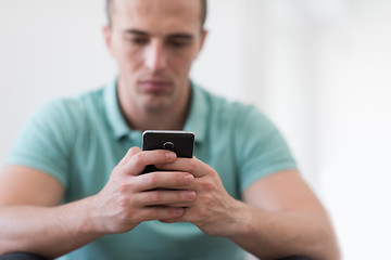 Image showing young man using a mobile phone  at home